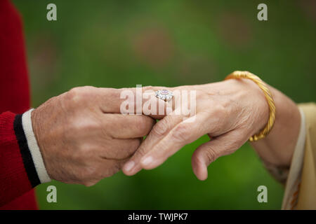 Old man placing ring on womans finger Stock Photo