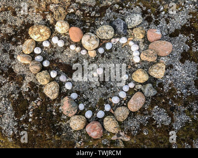 Heart shape from stones and shells on natural ground. Romantic love symbol, Valentine concept, top view Stock Photo