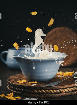 Blue bowl of corn flakes with milk splash Stock Photo