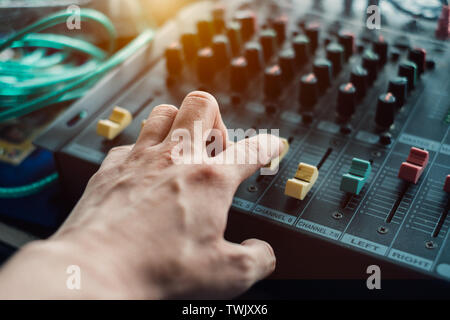 Close-up hand adjusting mixer sound on control audio panel Stock Photo