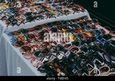 Variety of different coloured and shaped sunglasses on sale at a market stall. Stock Photo