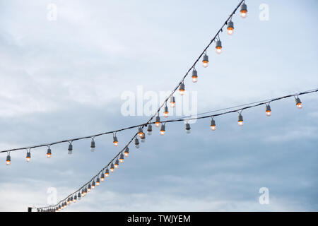 Antique light bulbs crossing with hanging on wire in blue sky Stock Photo