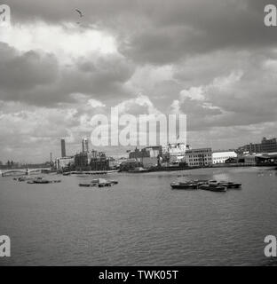 1950s, view of the river Thames and the various wharves and businesses along the riverbank, including the newspaper depots of the News Chronicle, and The Star and the warehouses of other companies such as Bowaters and Boots. The News Chronicle was a British daily newspaper - once owned by the Cadbury family - that ceased publication in 1960, when ir merged with the Daily Mail. As part of the same takeover, the London evening paper, The Star, was incorporated into the Evening News. Stock Photo