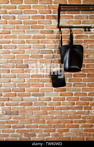 Modern hallway loft interior and black leather bags on hanger against brick wall. With copy space. Stock Photo