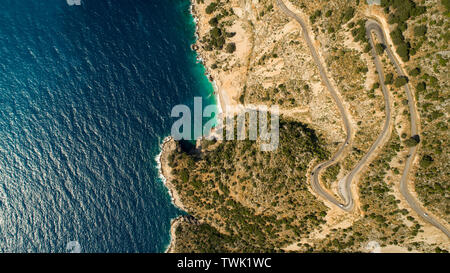 Aerial landscape of coastline and a road seascape. Car drives down the empty asphalt road running along the sunny Mediterranean shoreline of Turkey. Stock Photo