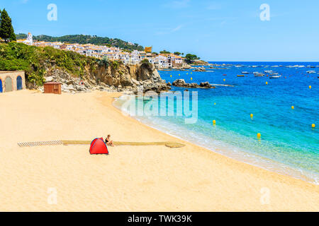 Red tent on amazing beach in Calella de Palafrugell, scenic fishing village with white houses and sandy beach with clear blue water, Costa Brava, Cata Stock Photo