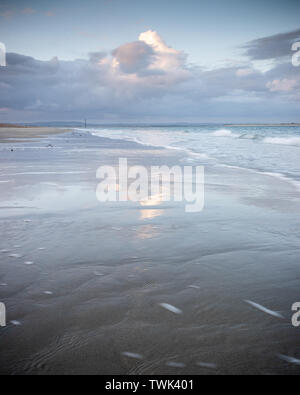 sunset clouds reflecting on wet sands at the beach Stock Photo