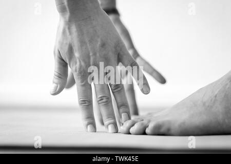 Close-up side view of the hands and feet of a young woman practicing Uttanasana or Standing Forward Bend yoga pose, horizontal view with copy space Stock Photo