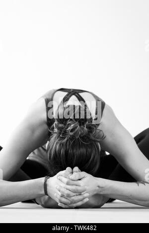 vertical close up of an unrecognizable dark haired european woman doing the star pose or tarasana yoga posture twk482