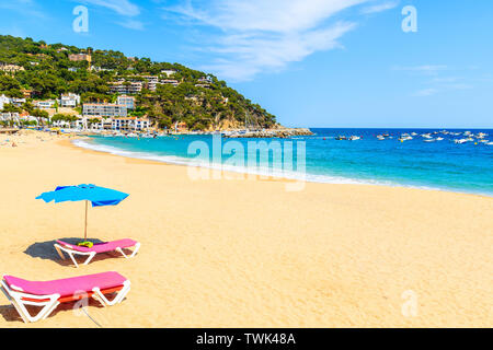 Sunbeds with umbrella on sandy beach in Llafranc village, Costa Brava, Spain Stock Photo