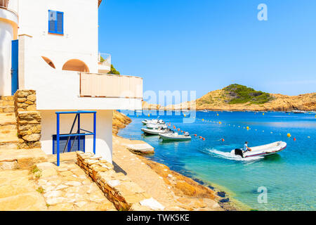 Dinghy boat sailing away from beach in Sa Tuna coastal fishing village, Costa Brava, Spain Stock Photo