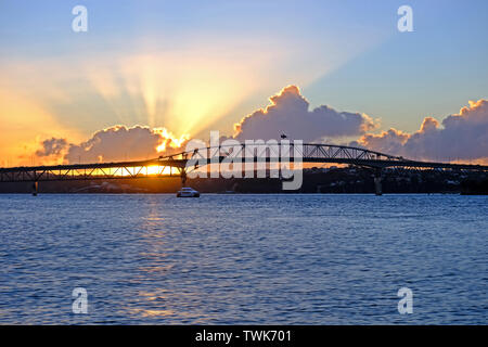 amazing sunset, flare though the clouds, auckland harbor bridge, new zealand Stock Photo