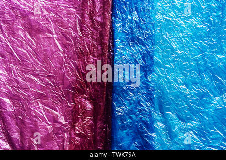 Close-up background of two pieces of different colors of plastic used packages, the texture of wrinkled polyethylene. Stock Photo