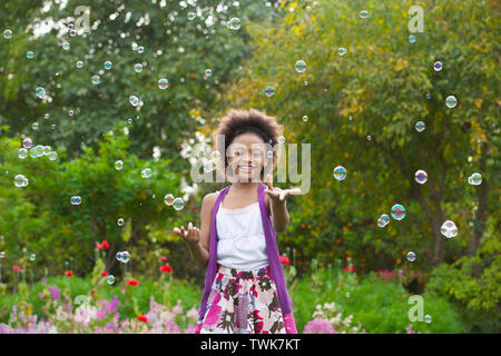 Girl trying to hold floating bubbles Stock Photo