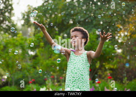 Girl trying to hold floating bubbles Stock Photo