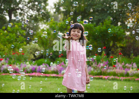 Girl trying to hold floating bubbles Stock Photo