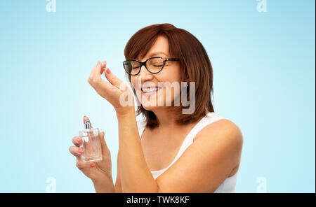 senior woman smelling perfume from her wrist Stock Photo