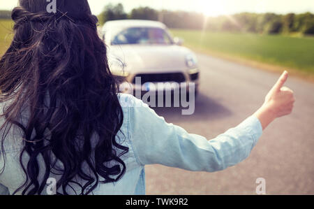 woman hitchhiking and stopping car with thumbs up Stock Photo