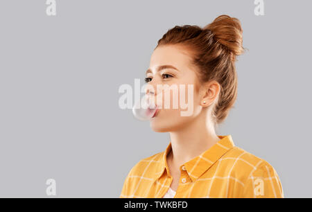 red haired teenage girl blowing bubble gum Stock Photo