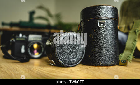 Old, vintage, retro style Takumar lens cover boxes and Spotmatic Pentax camera in the background on wooden table Stock Photo