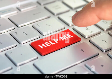 Keyboard - with a big HELP. Picture of red button on the keyboard with word of HELP ME. Finger presses the color button on the gray keyboard Stock Photo
