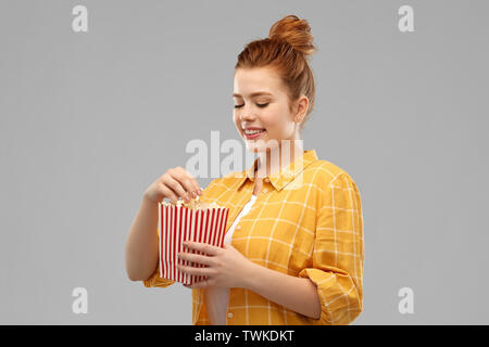 smiling red haired teenage girl eating popcorn Stock Photo