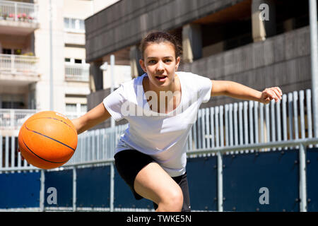 Teen girl playing basketball in an urban court Stock Photo