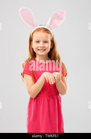 happy red haired girl wearing easter bunny ears Stock Photo