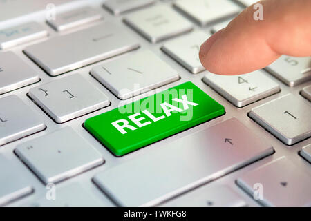 Time to relax concept. word relax written on computer keyboard. Finger presses the color button on the gray keyboard. Purchase buy tickets online. pla Stock Photo