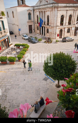 Conversano,Italy: unrecognizable people on the square of the Conversano,among the flowers and plants of the spring of Apulia. Stock Photo