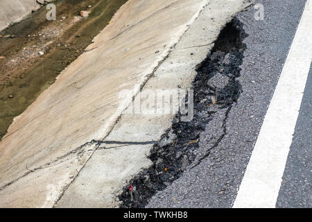 Cracked and broken of surface asphalt road on roadside Stock Photo