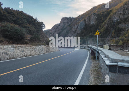 Asphalt road with traffic signs in valley on plateau Stock Photo