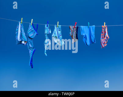 Swimsuit laundry on the clothes line on a blue background Stock Photo