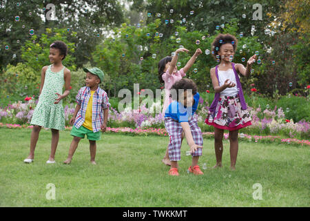 Children playing with floating bubbles Stock Photo