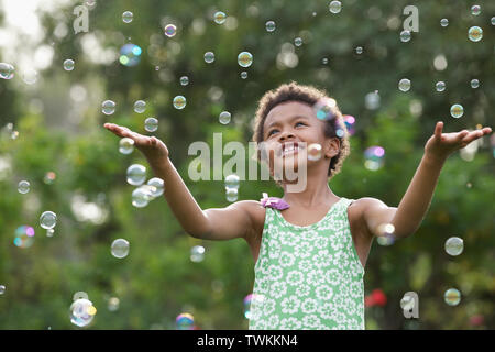 Girl trying to hold floating bubbles Stock Photo