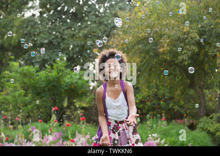 Girl trying to hold floating bubbles Stock Photo