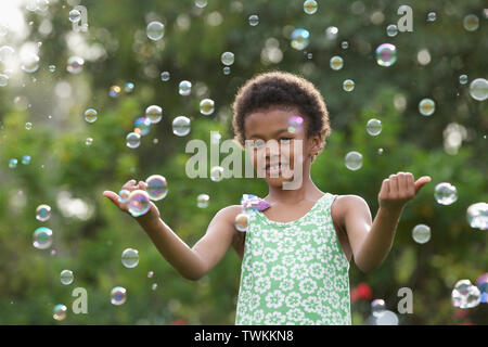 Girl trying to hold floating bubbles Stock Photo