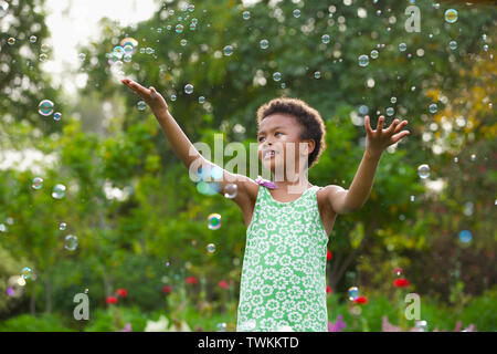 Girl trying to hold floating bubbles Stock Photo
