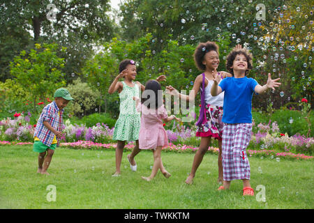 Children playing with floating bubbles Stock Photo