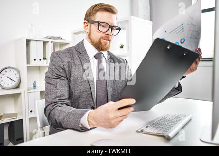 Mid age businessman working with dokuments at the computer in office Stock Photo