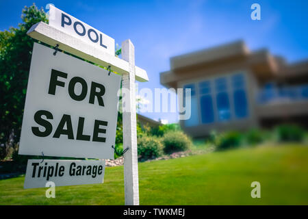 A Sale Sign For A Luxury Home With A Triple Garage And Swimming Pool In The Suburbs Stock Photo