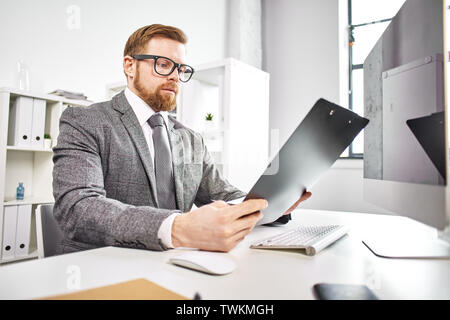 Mid age businessman working with dokuments at the computer in office Stock Photo