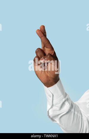 Male hand in white shirt demonstrating a gesture of waiting of good luck isolated on blue studio background. Concept of business, office, work. Negative space to insert your text or image. Stock Photo