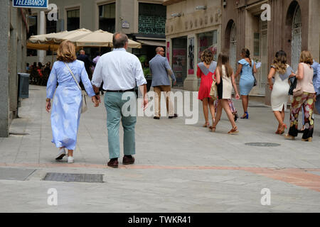 Middle aged couple holding hands while walking down a busy pedestrian walkway in Granada, Spain. Stock Photo
