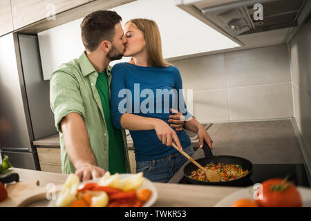 Young couple is preparing meal in their kitchen. Stock Photo
