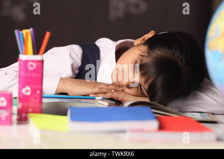 Schoolgirl napping on a desk in a classroom Stock Photo