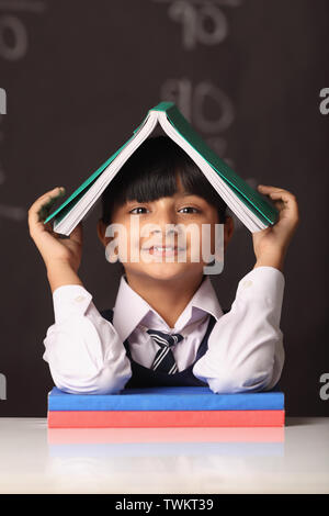 Schoolgirl holding her book on her head Stock Photo - Alamy