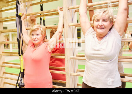 Senior women doing gymnastics on the wall bars in senior sport in back exercises Stock Photo