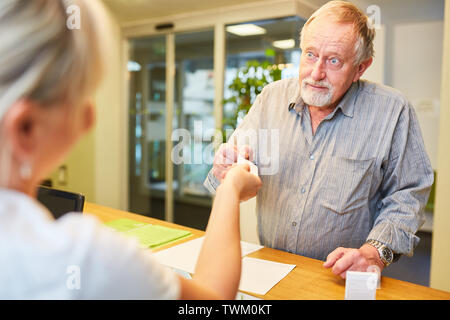 Senior man at the desk at the doctor or physiotherapist gets an appointment Stock Photo