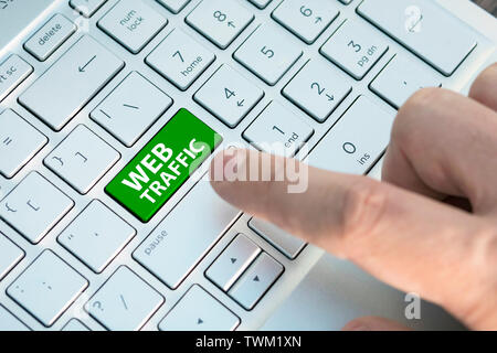 Keyboard with web traffic button. Computer white keyboard with web traffic button. A male finger presses a color button on a gray silver keyboard of a Stock Photo